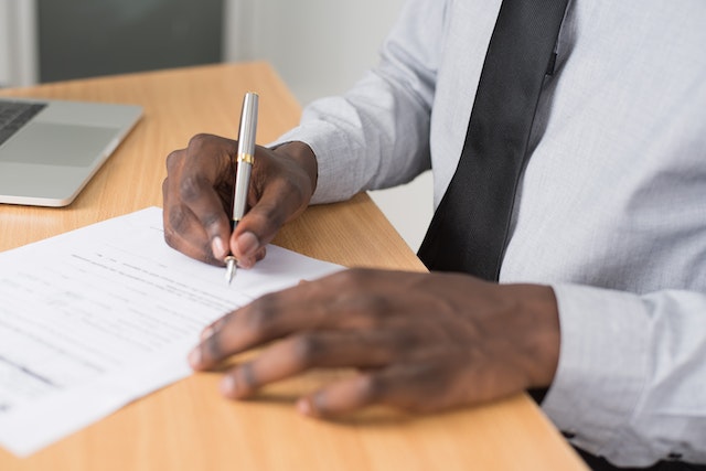 person holding a pen and signing a leasing contract